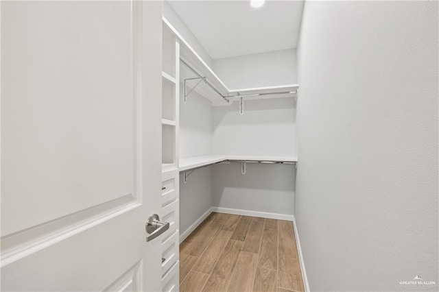 spacious closet featuring light hardwood / wood-style flooring and built in desk