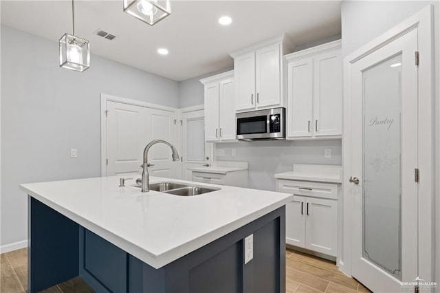 kitchen with white cabinetry, sink, an island with sink, and hanging light fixtures