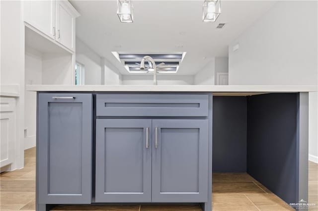 kitchen with white cabinetry, sink, gray cabinetry, and hanging light fixtures