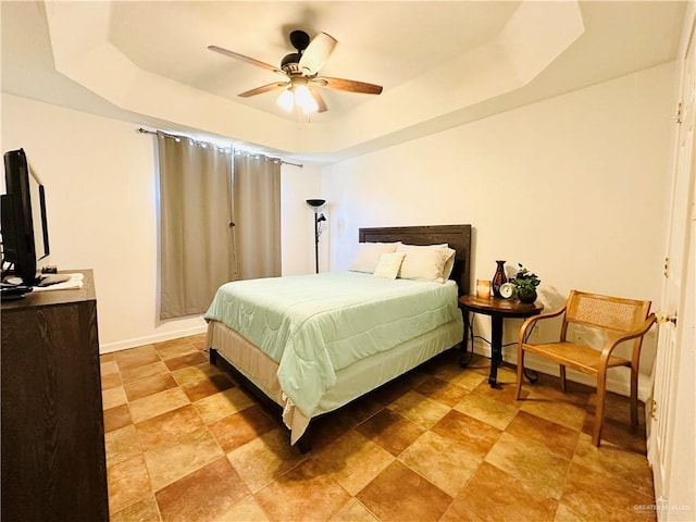 bedroom featuring a raised ceiling and ceiling fan