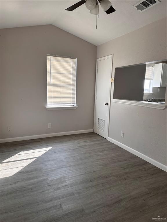 spare room with dark hardwood / wood-style floors, vaulted ceiling, and ceiling fan