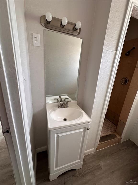 bathroom featuring a shower, vanity, and hardwood / wood-style flooring