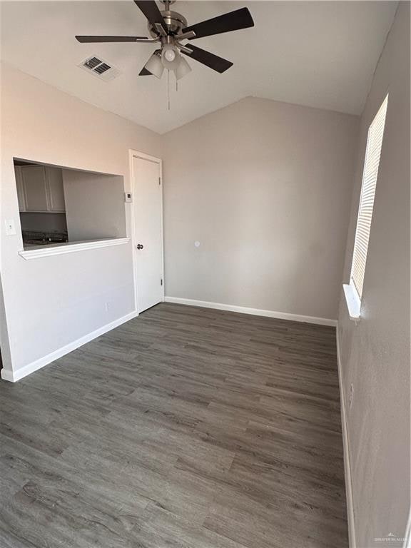 empty room with ceiling fan, dark hardwood / wood-style flooring, and lofted ceiling