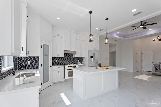 kitchen with white cabinetry, hanging light fixtures, oven, and a center island