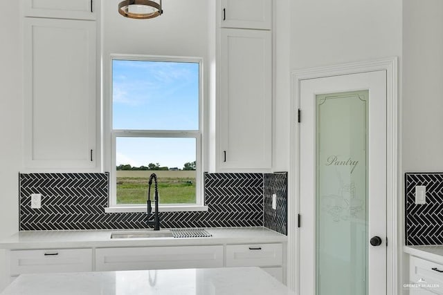 kitchen featuring sink, decorative backsplash, and white cabinets