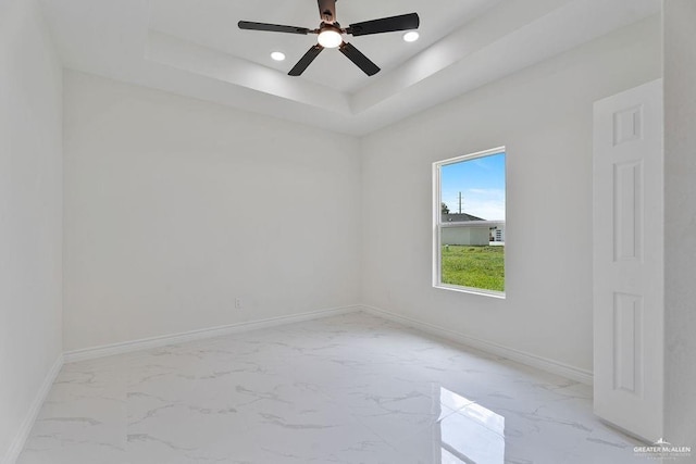 spare room with a raised ceiling and ceiling fan