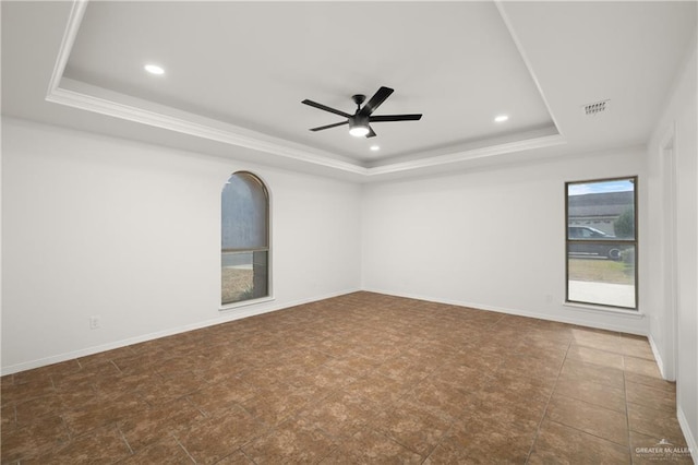 spare room featuring ceiling fan and a raised ceiling