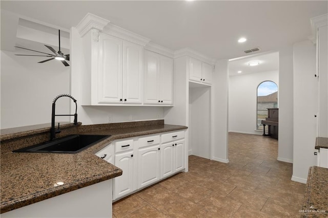 kitchen with white cabinetry, sink, dark stone countertops, and ceiling fan