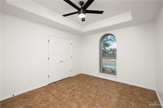 unfurnished bedroom featuring crown molding, a tray ceiling, a closet, and ceiling fan