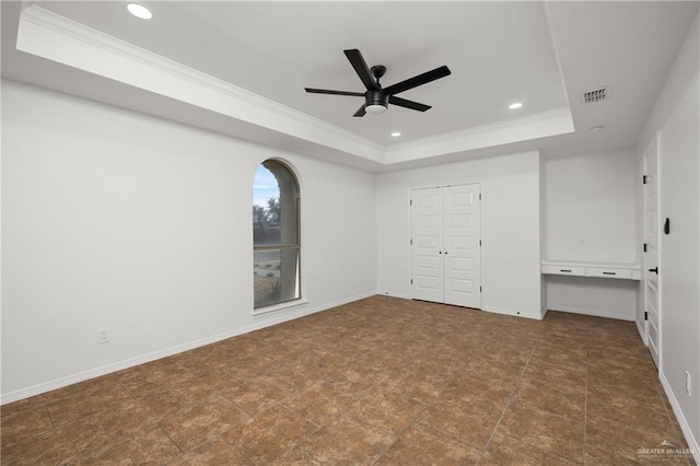 unfurnished bedroom featuring ornamental molding, a closet, ceiling fan, and a tray ceiling