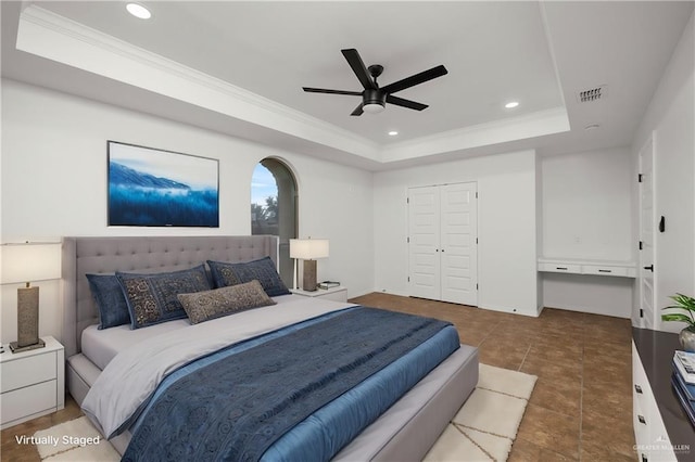 tiled bedroom with a closet, crown molding, a raised ceiling, and ceiling fan