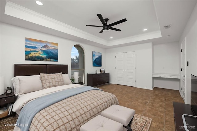 bedroom featuring crown molding, a tray ceiling, a closet, and ceiling fan