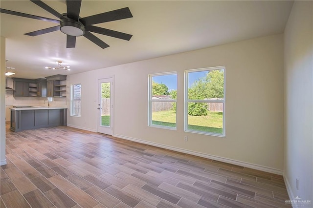 unfurnished living room featuring ceiling fan, dark hardwood / wood-style flooring, and sink