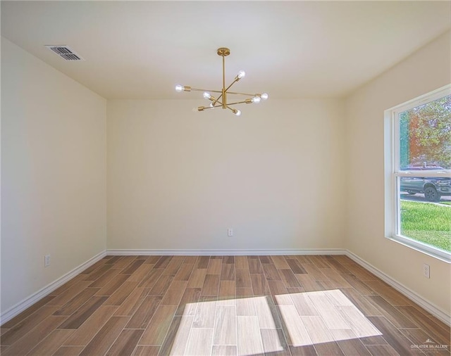 spare room with wood-type flooring and an inviting chandelier