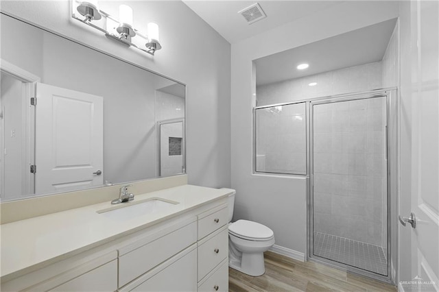 bathroom featuring vanity, hardwood / wood-style floors, a shower with shower door, and toilet