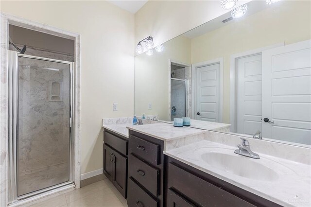 bathroom with visible vents, baseboards, vanity, a shower stall, and tile patterned floors