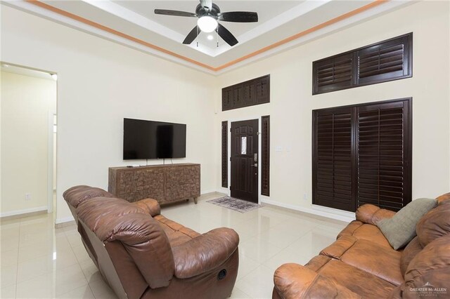 living area featuring a ceiling fan, baseboards, and light tile patterned floors