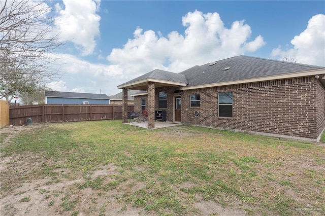 rear view of property with a yard, a fenced backyard, a patio, and brick siding