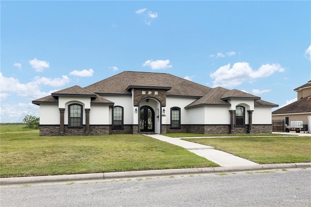 8605 Estrella Dr, Elsa, TX 78538 - view of front of house with french doors, stucco siding, a front yard, and stone siding