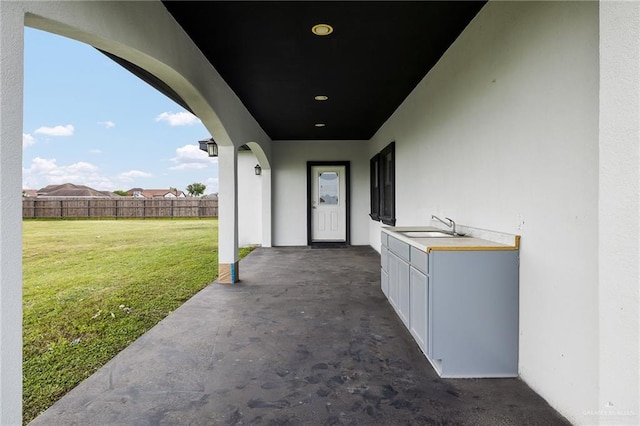 8605 Estrella Dr, Elsa, TX 78538 - entrance to property with fence, stucco siding, a patio area, a lawn, and a sink