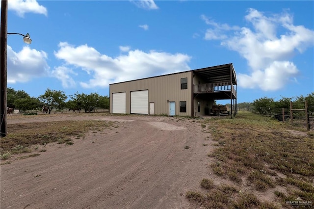 view of outbuilding featuring an outdoor structure, dirt driveway, and fence