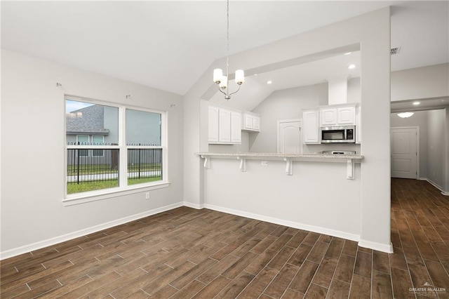 kitchen featuring white cabinetry, decorative light fixtures, dark hardwood / wood-style flooring, a kitchen breakfast bar, and kitchen peninsula