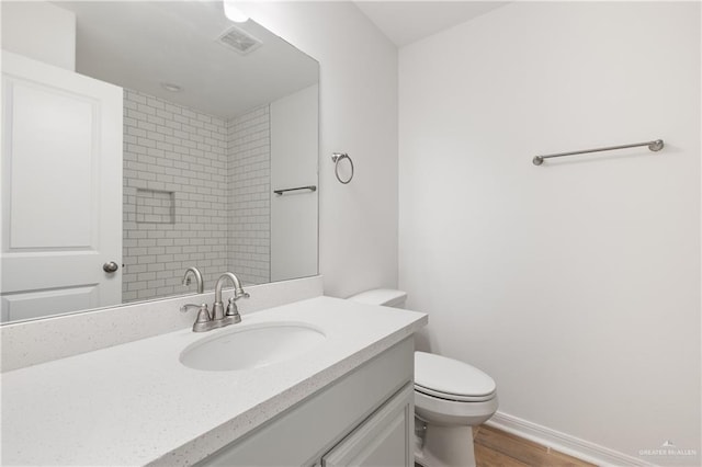 3213 El Paso Dr, Weslaco, TX 78599 - full bathroom with vanity, toilet, wood finished floors, and baseboards