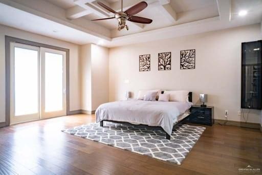 bedroom featuring access to outside, beamed ceiling, wood finished floors, and coffered ceiling