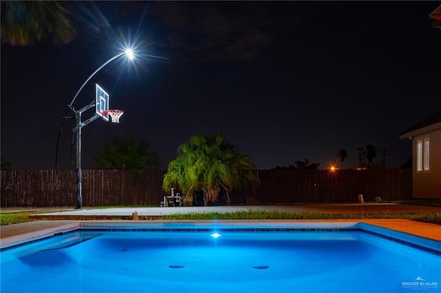 pool at twilight with fence and a fenced in pool