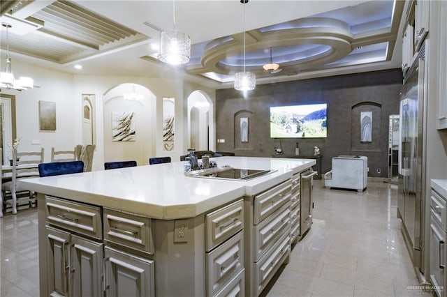 kitchen featuring coffered ceiling, arched walkways, light countertops, electric cooktop, and a center island