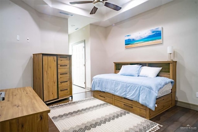 bedroom with wood finished floors, visible vents, baseboards, ceiling fan, and a raised ceiling