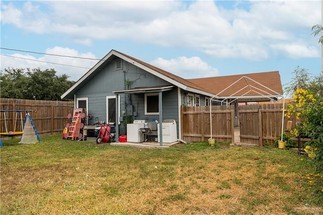 rear view of property featuring a lawn and washing machine and clothes dryer