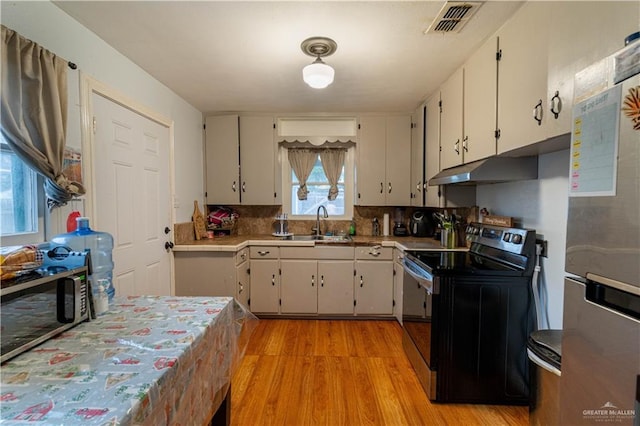 kitchen with stainless steel fridge, backsplash, sink, light hardwood / wood-style floors, and black electric range oven