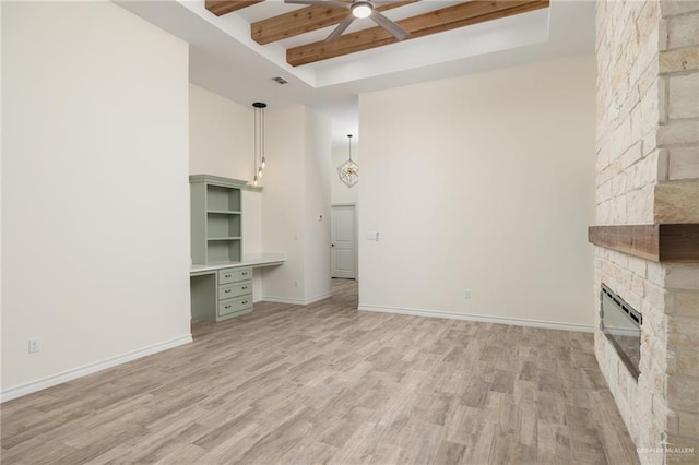 unfurnished living room with a fireplace, light wood-type flooring, a tray ceiling, and ceiling fan