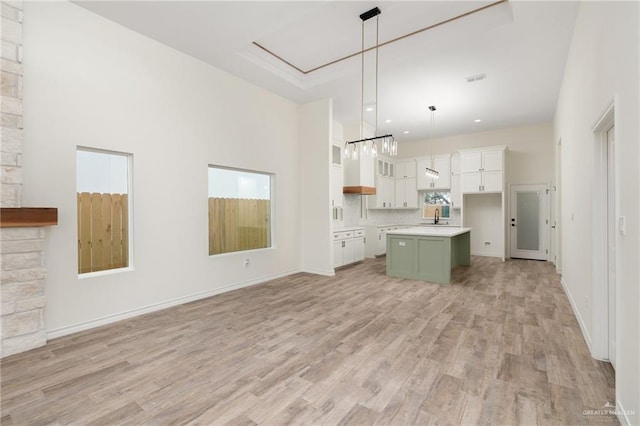 kitchen with white cabinets, decorative light fixtures, a kitchen island, and light hardwood / wood-style flooring