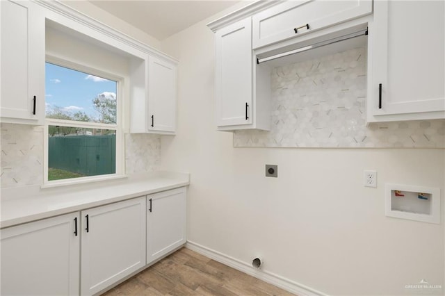 clothes washing area featuring electric dryer hookup, light hardwood / wood-style flooring, cabinets, and washer hookup