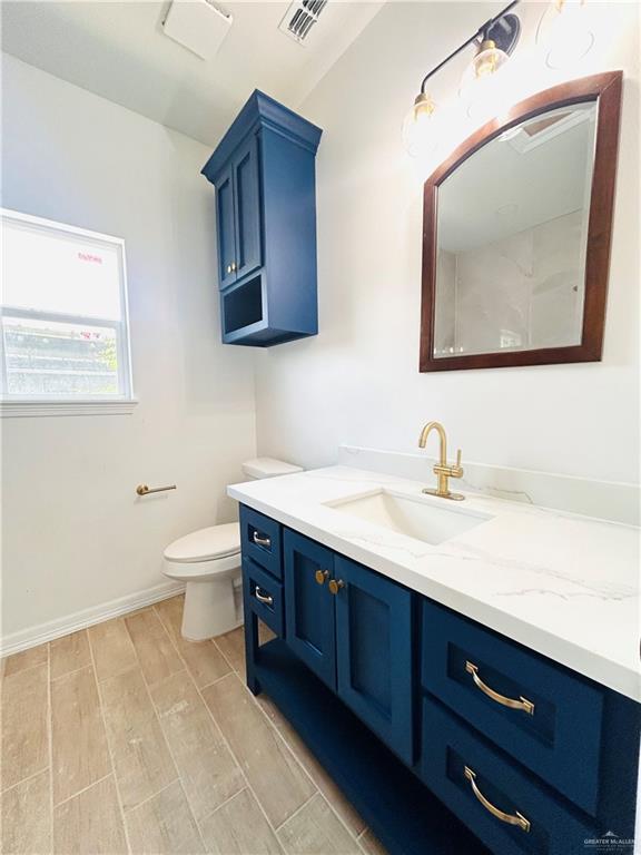 412 S Bowie Ave, Elsa, TX 78538 - bathroom with vanity, wood tiled floors, toilet, and baseboards