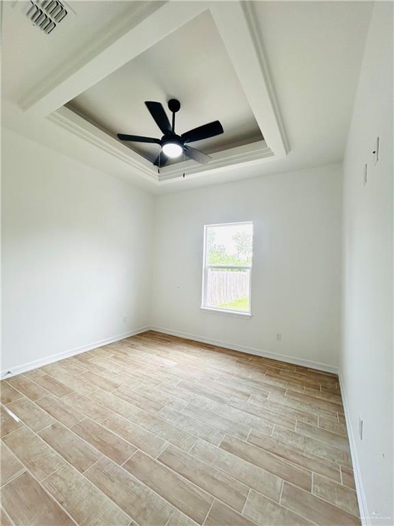 412 S Bowie Ave, Elsa, TX 78538 - spare room with a raised ceiling, light wood-style flooring, baseboards, and ceiling fan