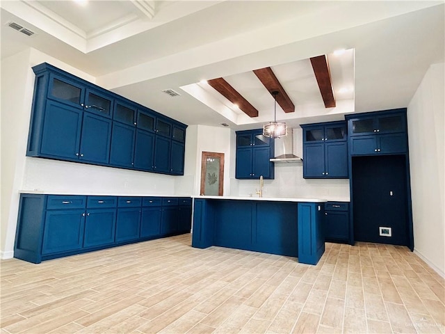 412 S Bowie Ave, Elsa, TX 78538 - kitchen with wall chimney exhaust hood, beamed ceiling, blue cabinets, light wood-type flooring, and light countertops