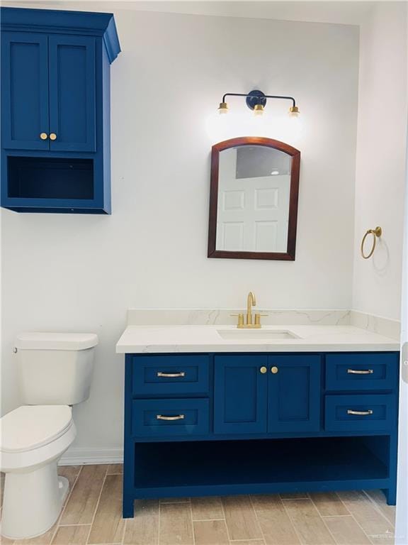 412 S Bowie Ave, Elsa, TX 78538 - bathroom featuring vanity, wood tiled floors, toilet, and baseboards
