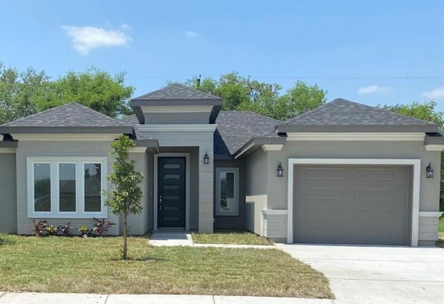 prairie-style home featuring a garage, a shingled roof, a front lawn, and stucco siding