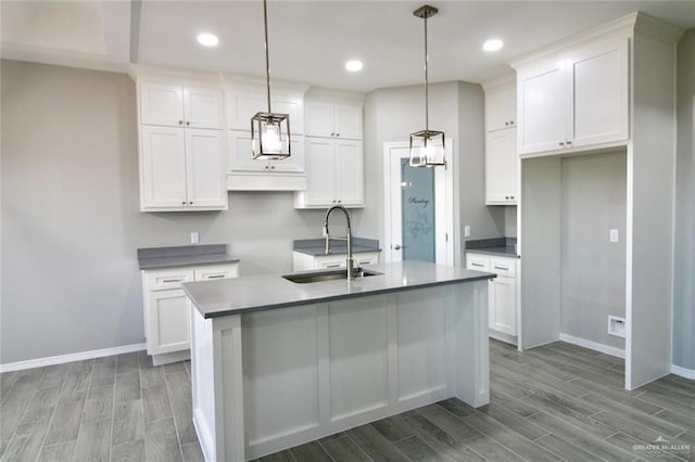 kitchen featuring a center island with sink, decorative light fixtures, and white cabinets