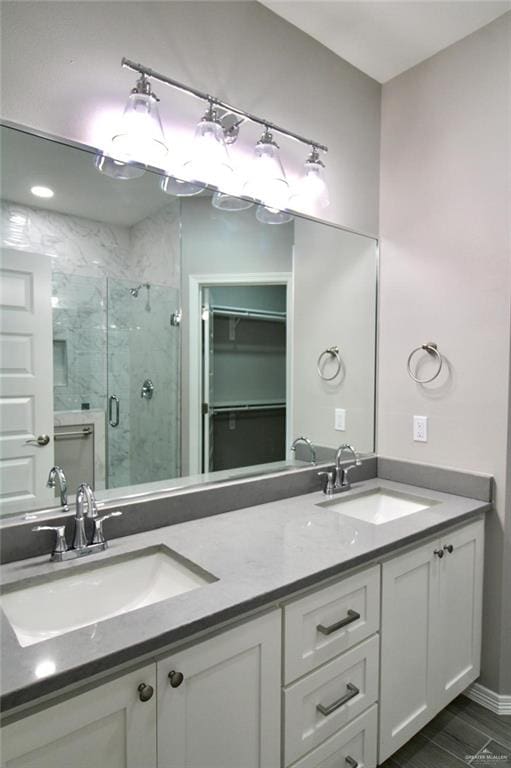 bathroom featuring double vanity, a stall shower, wood tiled floor, and a sink