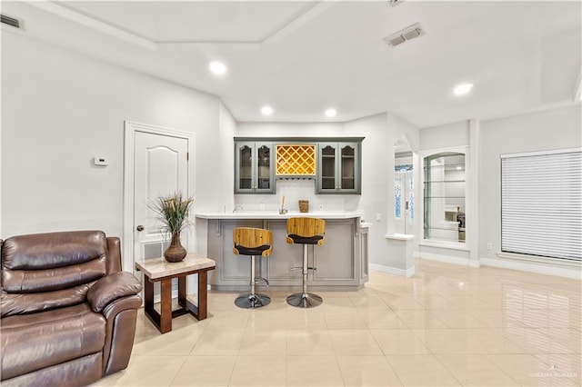 kitchen featuring gray cabinetry, a kitchen breakfast bar, light tile patterned flooring, and kitchen peninsula