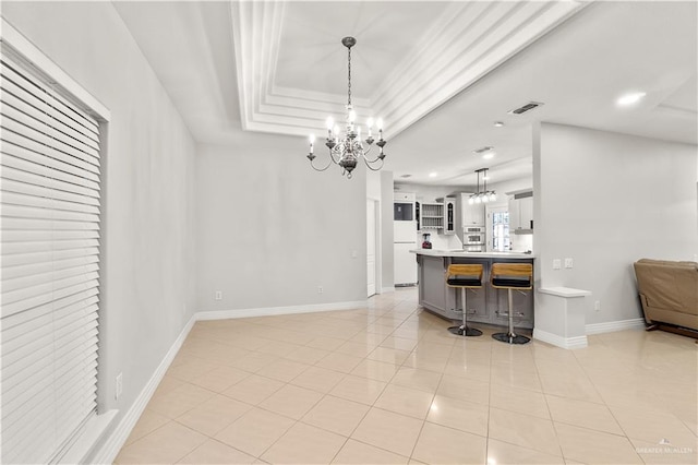 kitchen with a kitchen breakfast bar, light tile patterned floors, decorative light fixtures, an inviting chandelier, and white fridge