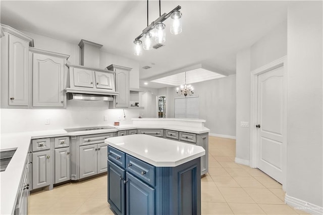 kitchen featuring hanging light fixtures, light tile patterned floors, a notable chandelier, black electric cooktop, and a kitchen island