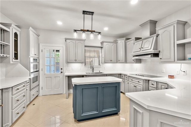 kitchen featuring sink, a center island, hanging light fixtures, cooktop, and light tile patterned flooring