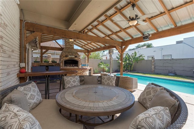 view of patio featuring ceiling fan, exterior fireplace, a gazebo, and a fenced in pool