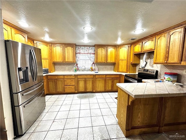 2724 La Villita St, Brownsville, TX 78521 - kitchen featuring range with electric stovetop, stainless steel fridge, a peninsula, brown cabinetry, and a textured ceiling