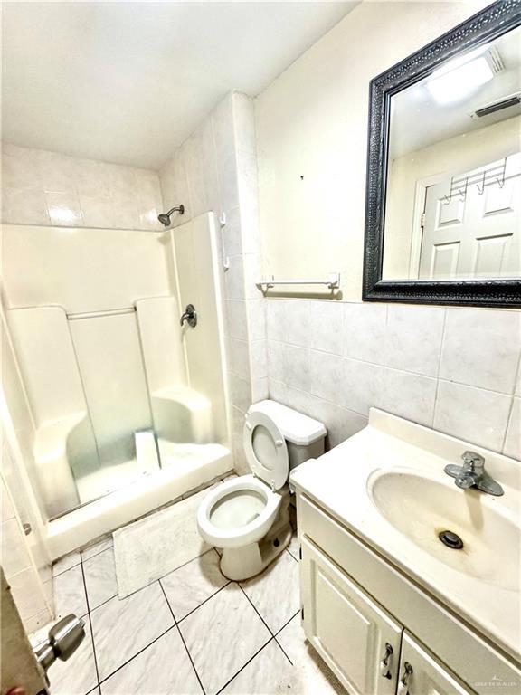 2724 La Villita St, Brownsville, TX 78521 - bathroom with a shower stall, tile walls, toilet, vanity, and tile patterned flooring